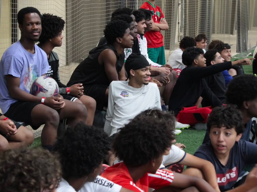 Players sitting shoulder to shoulder on the sideline, watching a game at an MYH tournament