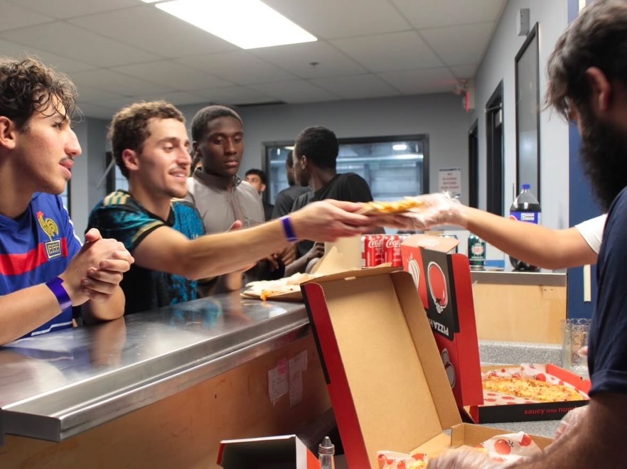 Pizza being handed across the counter to players after the games
